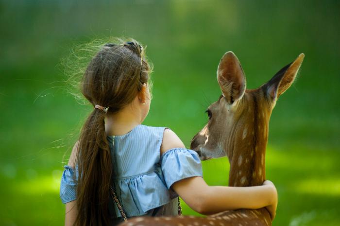 girl hugging a tame deer